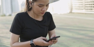 迷人的白人女运动员跑步时，坐在城市日落的街道边，在社交媒体上分享信息。女孩跑步戴耳机听音乐。