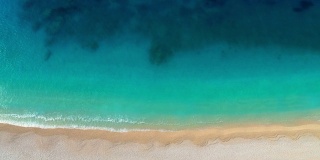 空中鸟瞰完美的绿松石海滩。Сlear蓝色的海水-完美的暑假。飞过白沙空旷的海滩