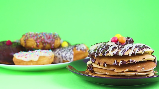 美味的巧克力煎饼和巧克力甜甜圈在绿色屏幕上为派对服务