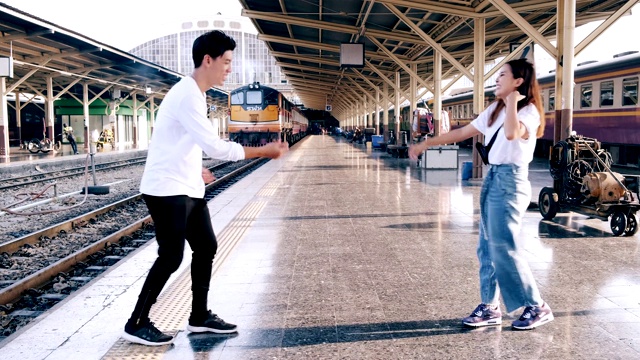 宽镜头的年轻潮人做自由式街舞在火车站等待火车。亚洲男人和女人。