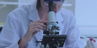 女科学家正在实验室里用显微镜进行研究。
