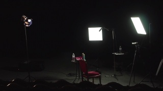 纪录片拍摄设置在剧场舞台上，三点灯光设置摄像机三脚架导演座视频素材模板下载