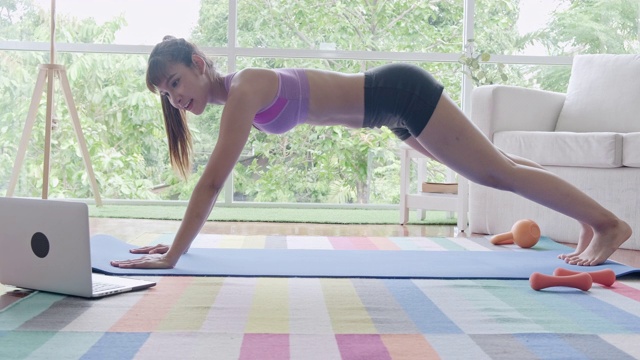 健身女性锻炼，腹肌，腹部，锻炼，听从笔记本电脑的指示。美丽的亚洲女人在体育。