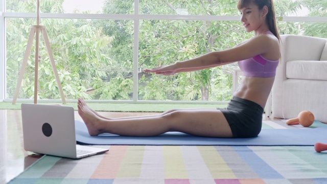 健身女性锻炼，伸展，腹肌，腹部，锻炼，听从笔记本电脑的指示。美丽的亚洲女人在体育。