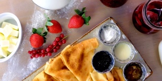 传统的俄罗斯煎饼，薄饼。配果酱，酸奶油，牛奶和草莓在盘子里。