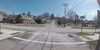 在一个阳光明媚的下午，一辆汽车在一个北美小镇的十字路口刹车
