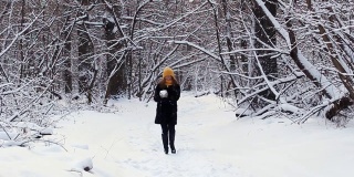 一个快乐的女孩走过冬天的森林，微笑，有一个好心情，玩雪，扔雪球