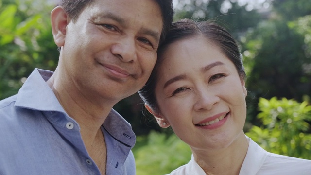 幸福的亚洲资深夫妇肖像与美丽的家花园的背景。