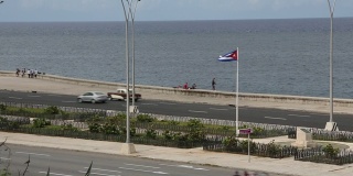 在哈瓦那主要公路上，汽车经过古巴国旗