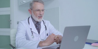 资深男医生通过笔记本电脑在线授课，进行医疗咨询