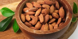 Almond Nuts to pour In Wooden Bowl. Healthy Food Concept.