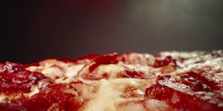 超近距离广角微距拍摄美味热气腾腾的深盘辣香肠披萨上的奶酪，新鲜出炉在冷却架上，在加热灯下，用移动相机拍摄向后滚动和结束与复制空间