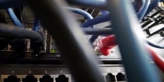 混乱的Cat5e以太网电缆插入闪烁的网络交换机与混乱的高速英特千兆位Cat5数据补丁线缆在IT组网柜的背景