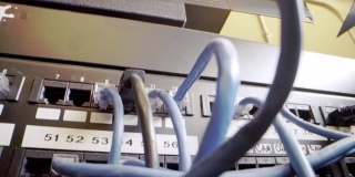 IT组网柜背景中插入交错的、杂乱的高速千兆因特网Cat5数据补丁线缆的闪烁网络交换机的Cat5e以太网线缆管理