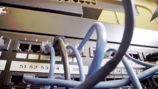 IT组网柜背景中插入交错的、杂乱的高速千兆因特网Cat5数据补丁线缆的闪烁网络交换机的Cat5e以太网线缆管理视频素材模板下载