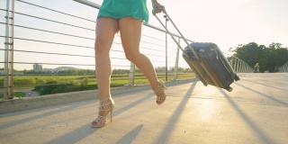 低角度:快乐的女人拿着她的行李箱在去机场的路上旋转。