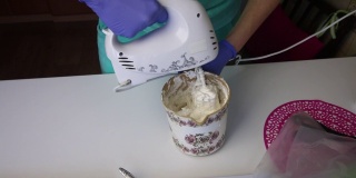 一个女人用搅拌机在一个容器里准备棉花糖。