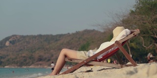 亚洲女性躺在沙滩上的躺椅上。睡在沙滩上，度假夏天的生活方式。