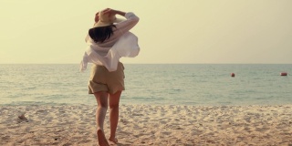 快乐的亚洲女人跑到海滩与手臂举起惊人的美丽的海洋沙的日落。