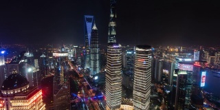 4k时间推移:陆家嘴金融区夜间空中俯瞰现代上海城市天际线，摩天大楼和交通信号灯