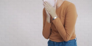 亚洲妇女戴口罩，以防止细菌传播和咳嗽，因为流感病毒感染的白色砖墙背景。预防传染病的概念。