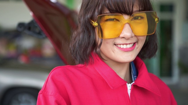 年轻的女技术员在车库得到红色制服的工作