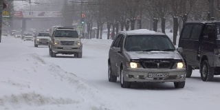 SlowMotion。降雪期间，汽车在海参崴的主要街道上行驶