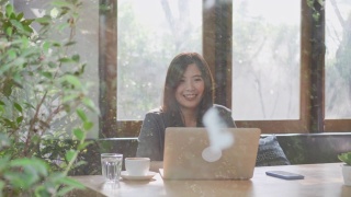 一个亚洲女人一边用笔记本电脑工作一边喝咖啡视频素材模板下载