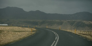 第一人称驾驶在黑暗的冰岛道路之间的草地和山的背景，冰岛