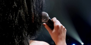一个长头发歌手的肖像在一个黑色烟雾的舞台在聚光灯下。铜
