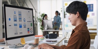 年轻的亚洲开发者，与创意团队在现代办公室的电脑桌面上编写手机游戏应用程序。Ux UI设计机构开发