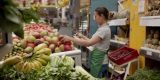 拉丁美洲的女售货员正在她的市场摊位上用写字板清点蔬菜