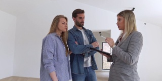 一位成功的女房地产经纪人向一对年轻夫妇展示一套空置的公寓