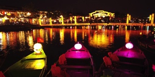 越南广南会安——2020年3月8日:在Thu Bon河上，游船带着漂浮的灯笼。人们在会安老城的桥上，联合国教科文组织世界遗产。
