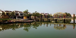 越南广南会安——2020年3月9日:游客在Thu Bon河上的桥上行走的时间序列，会安，联合国教科文组织世界遗产。传统的越南船只靠岸停泊。阳光明媚的一天。