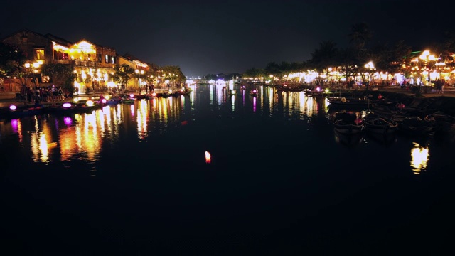 越南广南会安——2020年3月8日:在Thu Bon河上，游船带着漂浮的灯笼。视图。桥。人们在河边散步，会安，联合国教科文组织世界遗产。