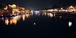 越南广南会安——2020年3月8日:在Thu Bon河上，游船带着漂浮的灯笼。视图。桥。人们在河边散步，会安，联合国教科文组织世界遗产。