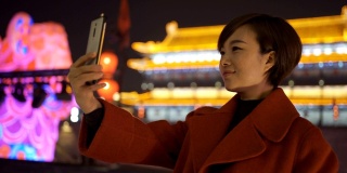 中国春节期间，一名女子用智能手机拍摄城市景观