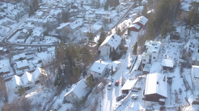 无人机拍摄到一辆红色汽车在雪地里穿过居民区