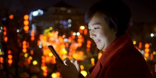中国春节期间，一名女子用智能手机拍摄城市景观
