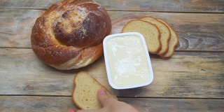 一位女性的手用一把刀在白面包上抹黄油。