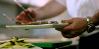 在一家餐馆里，厨师用盘子盛着一些刚烤好的羊肉串