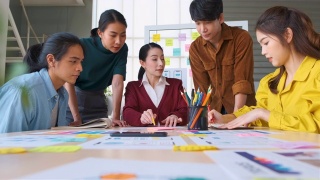 亚洲女性领导者建议ux/ui设计师在现代办公室的桌上进行手机应用界面线框图设计。创意数字发展机构视频素材模板下载
