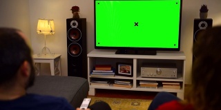 一对夫妇在家里看彩色键绿屏电视