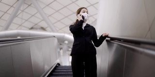 在新型冠状病毒感染的情况下，年轻的亚洲女性戴着白色外科口罩，在地铁上使用手机