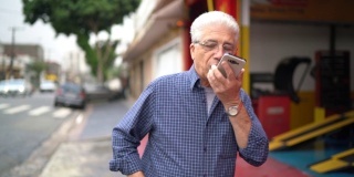 一位老人一边在城市里行走一边用手机打电话