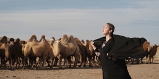 美丽的女子民族黑衣服，阿拉伯长袍走草原骆驼，沙漠，缓慢