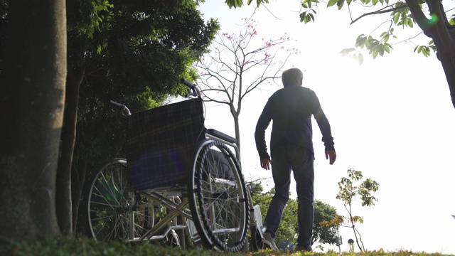 坐在轮椅上的亚洲老人在公园里伸展双臂