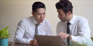 商人和合作伙伴一起讨论在笔记本电脑上的业务表现