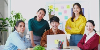 描绘快乐亚洲商业，创意企业家团队会议和头脑风暴在办公室，亚洲青年团队合作伙伴的微笑和看着相机